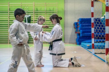 Trenerka wiążę pas w taekwon-do dziecku