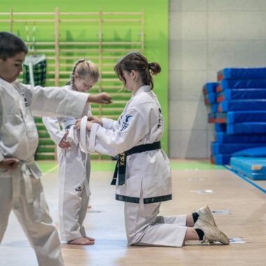 Trenerka wiążę pas w taekwon-do dziecku