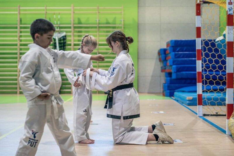 Trenerka wiążę pas w taekwon-do dziecku