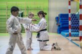 Trenerka wiążę pas w taekwon-do dziecku